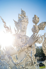 white scultpure of buddha holding flowers