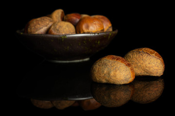 Lot of whole sweet brown chestnut in dark ceramic bowl isolated on black glass