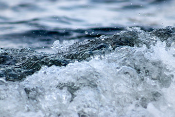 Waves close-up with spray and foam on the seashore is an abstract background. Close-up, shallow focus.