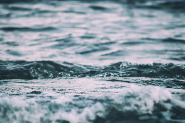 Waves close-up with spray and foam on the seashore is an abstract background. Close-up, shallow focus.
