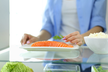 Portrait of female standing near open fridge full of healthy food, vegetables and fruits.