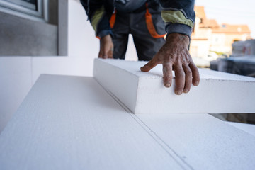 Worker use pen to mark the correct length and dimension of styrofoam during the wall insulation process at the construction site to cut the right size of the board