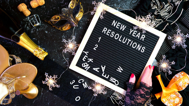 New Year's Eve resolutions flatlay with letter board and black and gold party decorations.