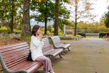 公園　ベンチ　女性　寒い　紅葉