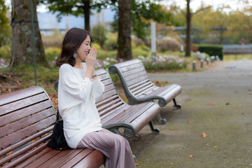 女性　ベンチ　寒い　秋