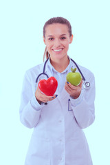 Beautiful smiling female doctor holding red heart and green apple. Woman doctor