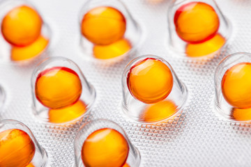 Metal drug blister with red orange medicine capsules. Vibrant color cure in transparent silver...