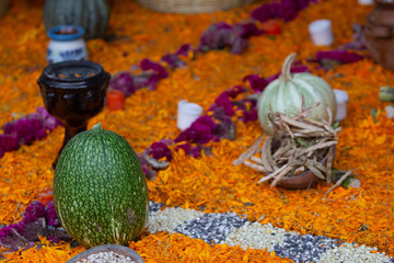 a mystique scene of an altar for the day of the dead in mexico with a pumpkin on a carpet made with petals of marigold flowers