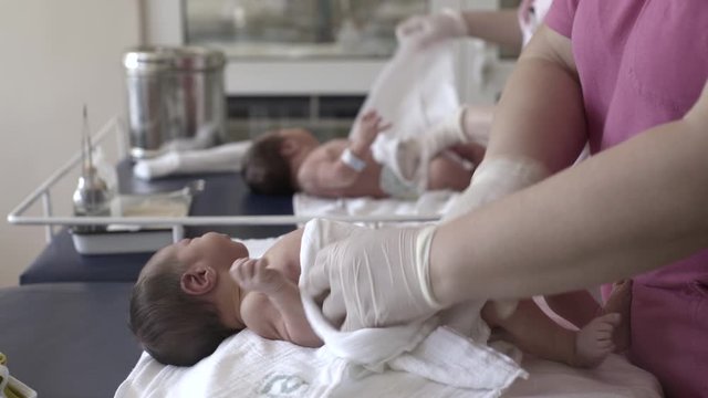 Midwives changing diapers newborn babies at maternity ward, close-up hands.