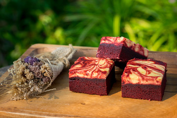 Red velvet cream cheese brownies on wooden plate