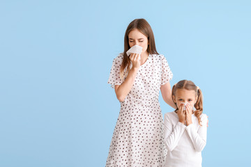 Young woman and little girl suffering from allergy on light background