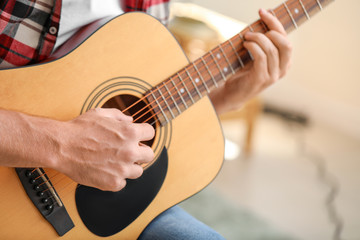 Handsome man playing guitar at home, closeup