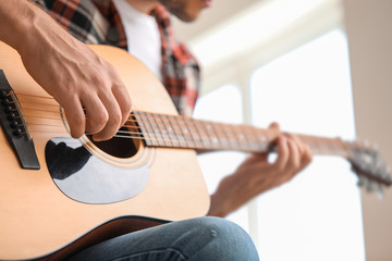 Fototapeta premium Handsome man playing guitar at home, closeup