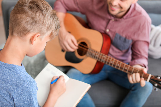 Little boy and his father with guitar at home