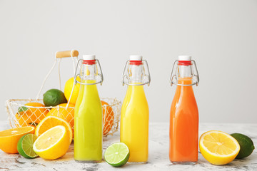 Obraz na płótnie Canvas Bottles of fresh juices with ingredients on grey background