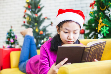 Fototapeta na wymiar Cute asian teenager girl reading a book in Christmas celebration