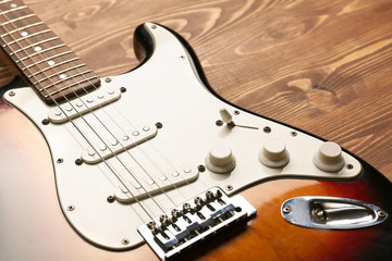 Modern bass guitar on wooden background, closeup