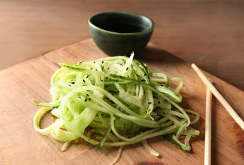 Asian vegetable salad, soy sauce and chopsticks on wooden background