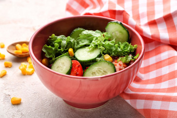 Bowl with fresh vegetable salad on light background