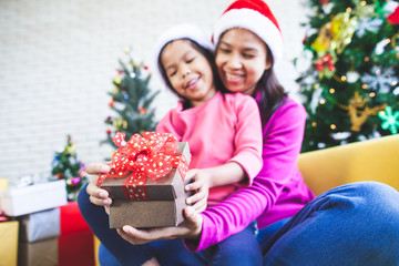 Cute asian child girl with her mother holding beautiful gift box and surprise with gift in Christmas celebration