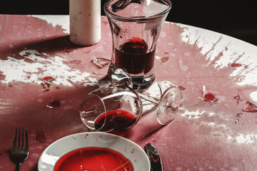 Broken goblets and broken glass on a table filled with red wine.
