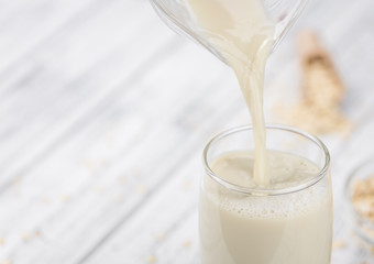 Portion of healthy Oat Milk on an old wooden table (selective focus; close-up shot)