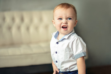 A small blond chubby boy shows a grimace. The boy growls at the camera. Horizontal photography