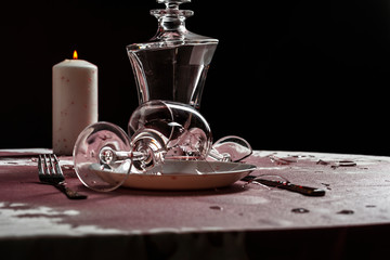 Broken goblets and broken glass on a table filled with red wine.