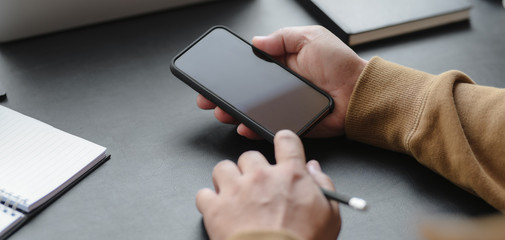 Close-up view male freelancer looking at his smartphone