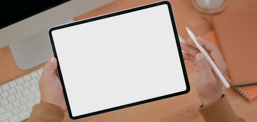 Close-up view of male freelancer working on his project with blank screen tablet