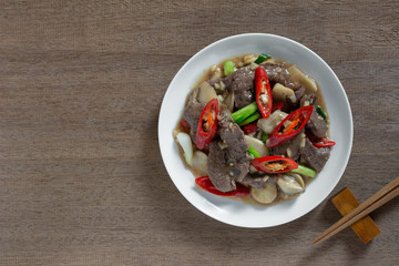 top view of stir fried beef with oyster sauce in a ceramic dish on wooden table. asian homemade style food concept.