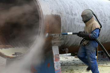engineer sandblasting a steel casing