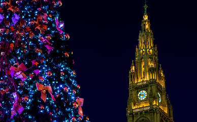 Christmas tree with The illuminated clock tower of city hall - rathaus in Vienna at night, Austria.