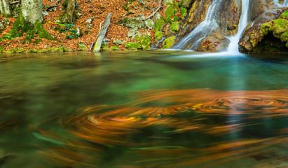 Brigth and warm colors and a beautiful stream and waterfalls in a wild mountain location in autumn