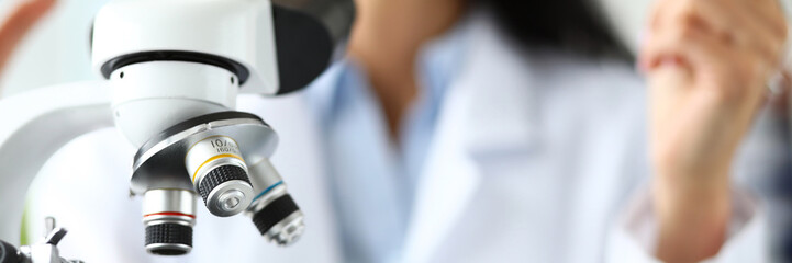 Fototapeta na wymiar Scientific microscope lens with female analyst in background