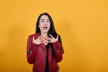 Beautiful happy young woman wearing red jacket put hands on body found out about winning isolated over yellow wall background studio portrait. People lifestyle fashion concept. Mock up copy space