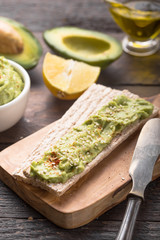 Two crackers with green  hummus, delicious cream of chickpeas and avocado on a wood background.