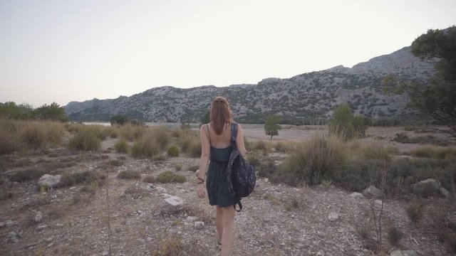 Beautiful red-haired woman traveler walks and has a good time on the rocky island of Mallorca. Slow motion shot of Balearic island in Spain