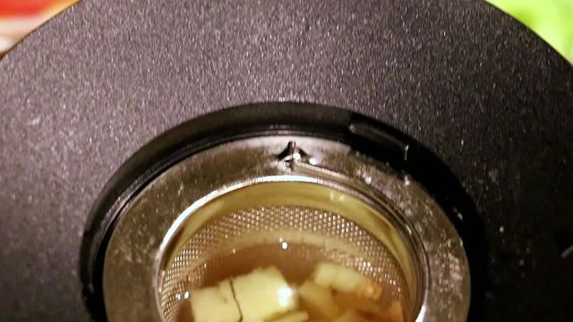 The leaching of ginger tea in a jug with filter on a table full of Thai food.