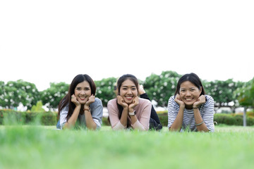 Group Cheerful young Asian woman in casual clothes three people laying down on grass together in the park. Look at the camera. Happy vacations. with Copy space