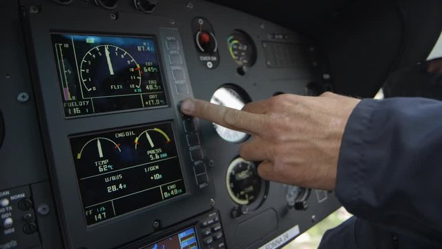 close up of helicopter cockpit intruments and pilots finger adjusting displays - during flight