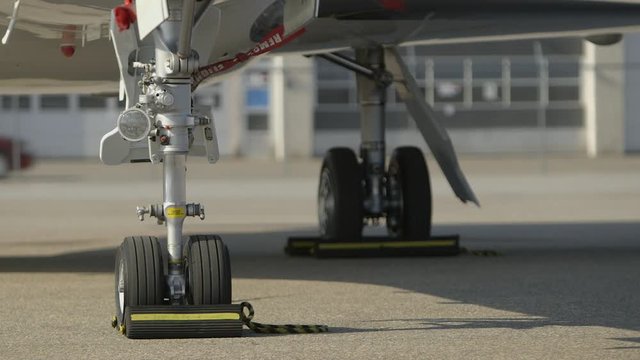 close up scene of business jets landing gear and underside of fuselage  - front side view - parked on tarmac