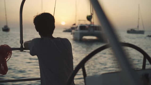 Man on a yacht enjoys sunset on Cala Saona bay. Luxury yacht near the Formentera island. Slow motion