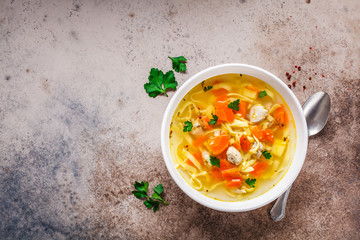 Chicken noodle soup with parsley and vegetables in a white plate, top view. - obrazy, fototapety, plakaty