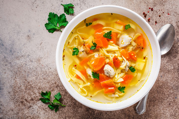 Chicken noodle soup with parsley and vegetables in a white plate, top view. - obrazy, fototapety, plakaty