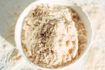 Close up scoop of protein powder on white background top view. Sports nutrition.