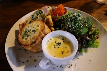 A lunch plate with corn soup and Italian salad
