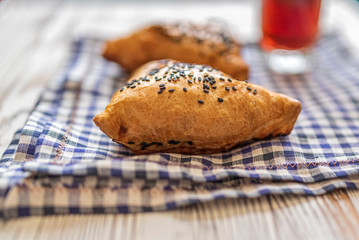 Samsa with meat on a napkin in a cage, next to a glass of juice. Photographed from above close-up.