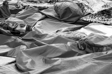 Synthetic fabrics to create inflatable forms of attractions lie on the plane crumpled abstract mass, preparation for the holiday, black and white image, close-up.