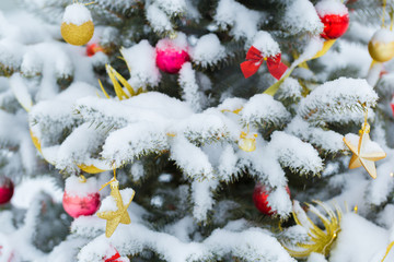 Christmas tree in snow background. New Year composition with fir tree, balls and lights and bokeh.